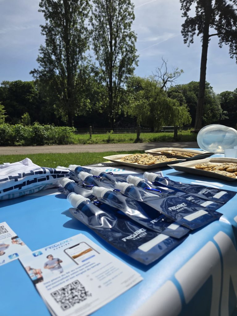 Image de la table FREQUENCE Running durant l'évènement des 10 ans de la marque, avec sur la table les flasques personnalisées FREQUENCE Running, les flyers FREQUENCE Running avec le QR code, les cookies maison. 